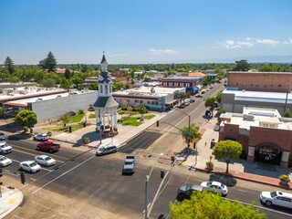 High-angle view of Red Bluff town square with a clock tower, businesses, and cars. Traffic flows...