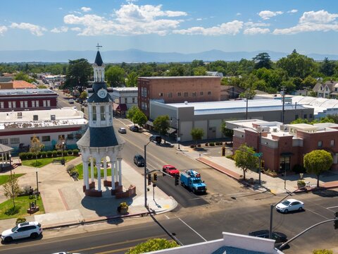 Aerial view of Red Bluff town square, showing a clock tower, businesses, and traffic. Cars and a utility truck are visible on the street. The Cone & Kimball Tower, Red Bluff, California, USA