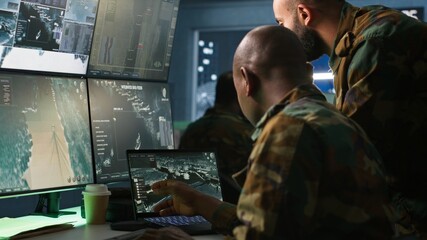 Military soldier in mission control center, overseeing national safety operations using notebook...