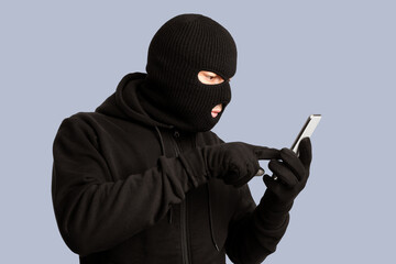 Scam Concept. Masked villain touching a smart phone screen, isolated on white studio background