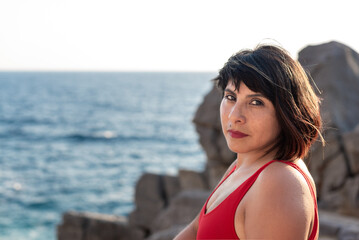candid portrait of beautiful woman in her 40s in swimsuit with blurred background of Mediterranean sea. Portrait with Polaroid analogic film vibes and style.