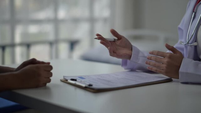 A doctor is talking to a patient in a hospital room. The patient is holding a pen and the doctor is holding a clipboard. Scene is serious and professional