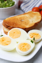 Hard boiled eggs with bread on light table, closeup