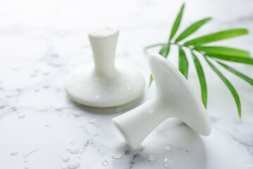 Wet spa stones and green palm leaf on white marble table, closeup. Space for text