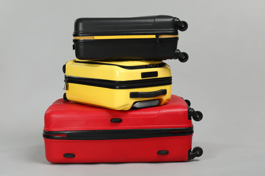 Stack of colorful suitcases on grey background