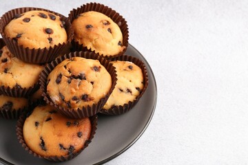 Delicious muffin with chocolate chips on light grey table, closeup. Space for text