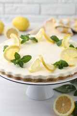Delicious lemon cheesecake with mint and fresh fruits on white wooden table, closeup