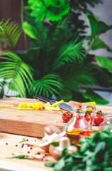 Cooking with nature: green and organic culinary setup. Raw potatoes cut into strips on oak cutting board with vegetables, herbs and spices on cozy kitchen with kitchenware and ingredients for cooking