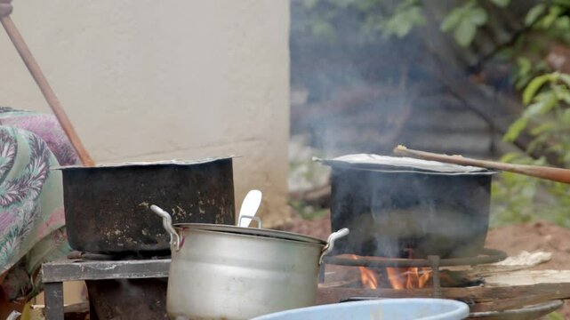 A woman stirs a large pot of food cooks over an open wood fire in Ethiopia, Africa.