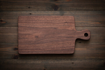 wooden board on wooden background. Handmade walnut wood chopping board on old wooden table.
