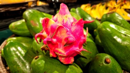 Dragon fruit, pitaya or strawberry pear display at supermarket. Dragon fruit with green avocado blurry background.