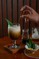 Es Cendol, a traditional indonesian beverage made with coconut milk, added with palm sugar syrup and pandan-flavored green rice flour jelly, served cold with ice cubes. Served on wooden table 