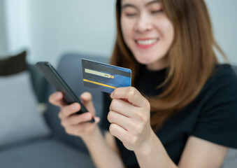 Asian woman while using credit card for shopping online on mobile phone applications.