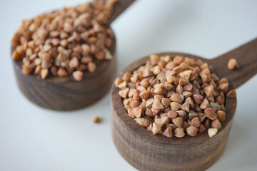 Buckwheat grains in wooden measuring cups on a clean surface
