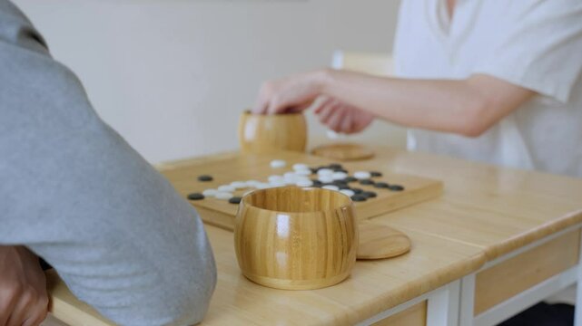Close up of young men play board game Go during competition in community. 