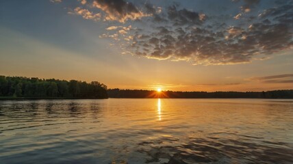 Obraz premium Golden Summer Sunrise Reflection over Calm Lake with Dramatic Sky and Lush Green Forest at Horizon