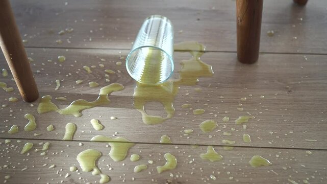 Glass falls and spills liquid onto wooden floor in unfortunate mess
