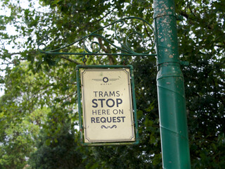 A sign says ' Trams Stop Here On Request' hanging from a post