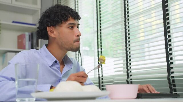 Asian young businessman eating Chinese dimsum while working in office. 