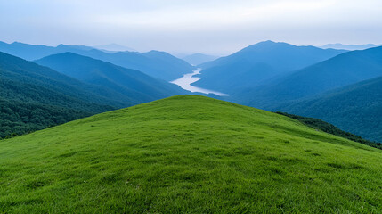 Fototapeta premium Mountaintop meadow overlooking valley, lake, and distant hills; scenic nature wallpaper