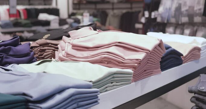 Colorful polo shirts neatly stacked on retail display, showcasing folded garments with clean arrangement highlighting clothing store merchandise variety