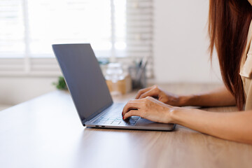 Shot of sad young asian woman overthinking while holding laptop computer and mobile phone sitting on the sofa at home
