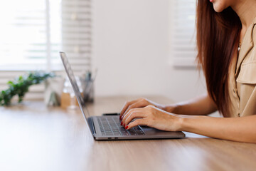 Brunette mid aged business asian woman sitting at the office using laptops for work.Technology business planning.