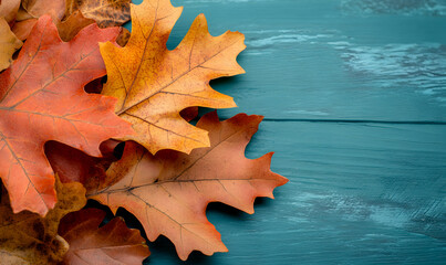Obraz premium Autumnal oak leaves on a teal wooden background. Perfect for fall-themed designs, cards, or blogs.