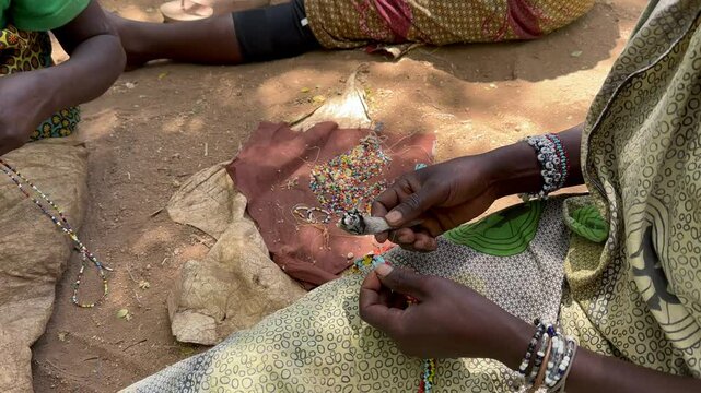 Close-up of Hadzabe women making jewelry from plastic beads. Lake Eyasi, Tanzania.