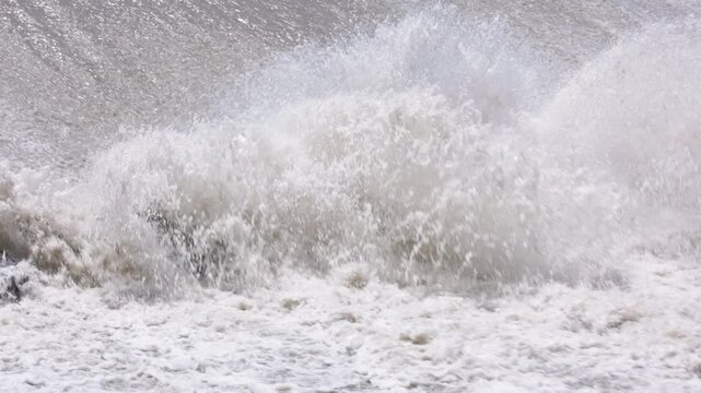 row of chute dentate blocks in concrete water spillway channel slope slowing down splashing flow of water running down.