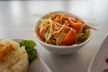Papaya salad yummy or somtum is a spicy Thai foods in white bowl.