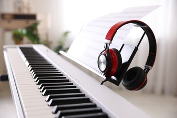 Synthesizer with music sheet and headphones indoors, closeup