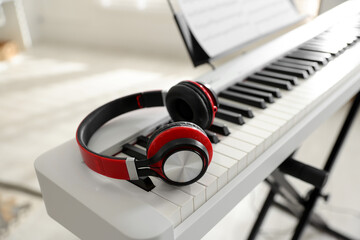 Synthesizer with music sheet and headphones indoors, closeup