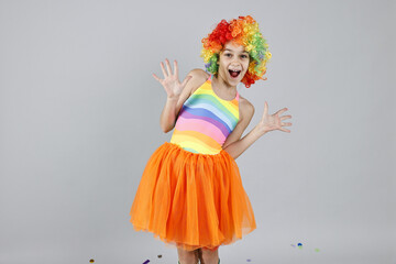 Happy girl dressed like clown on grey background. Surprise party