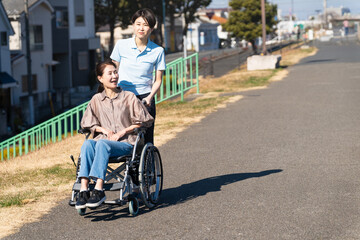 車椅子を押して散策する女性と介護士