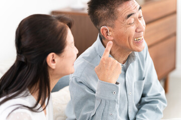 補聴器を付けた熟年男性と喜ぶ女性