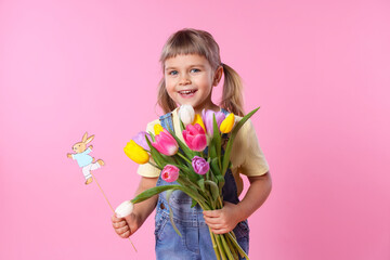 Smiling little girl with bouquet of tulips and decorative Easter bunny on pink background