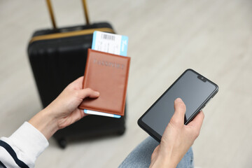 Traveller with passport, flight ticket and smartphone indoors, closeup