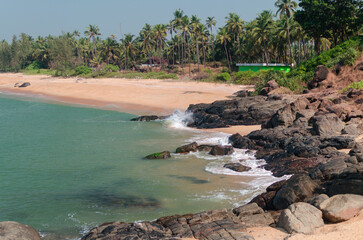 tropical beach with palm trees and rocks on the sea shore, Kerala, India