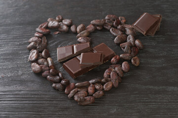 Cocoa beans arranged in a heart on a dark wooden background
