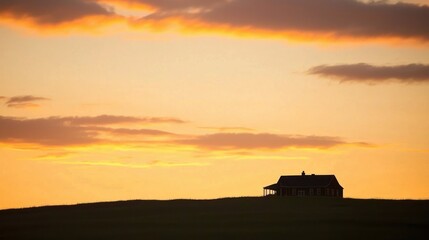 Silhouette of a Rural Farmhouse on a Hill at Sunset with Warm Orange Sky and Clouds Serene Countryside Landscape Capturing Tranquility and Natural Beauty