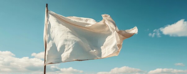 White flag waving gently against a clear blue sky, perfect for design mockup and creative projects