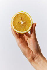 Hand holding half an orange with a slice on a white background