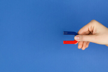 Woman with horseshoe magnet on blue background, closeup. Space for text