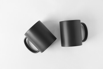 Two blank black mugs on white background, top view. Mockup for design