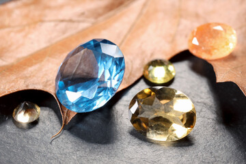 Beautiful shiny gemstones and dry leaf on black background, closeup