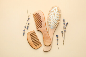 Wooden hair brush, combs and lavender flowers on beige background, flat lay