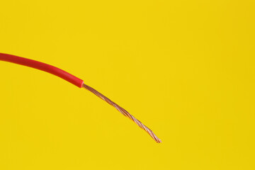 Red stripped electrical wire on yellow background, closeup