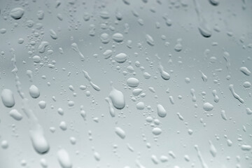 Water drops on light glass surface, closeup