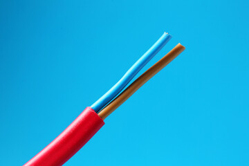 Red stripped electrical wire on light blue background, closeup